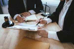 Lawyers reviewing and signing a legal contract at a desk with a gavel and scales of justice, representing legal consultation